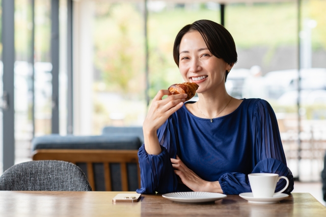 パンを食べながら微笑んでいる40代女性